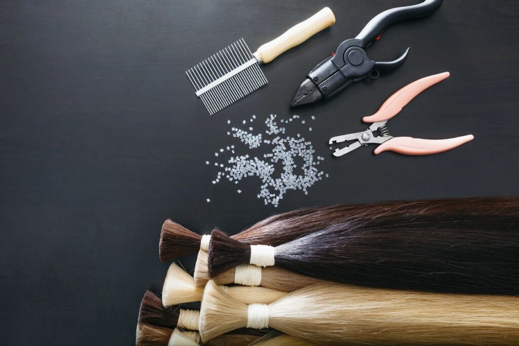 Hair cutting tools beside a bunch of different colored hair extensions