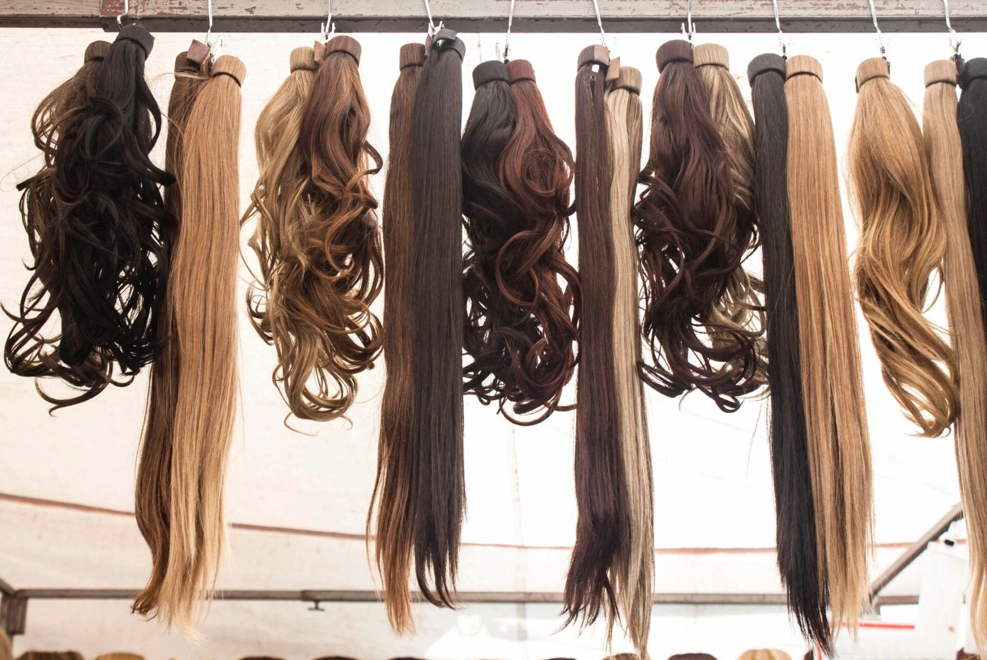 Different types of hair extensions hanging on a wooden pillar