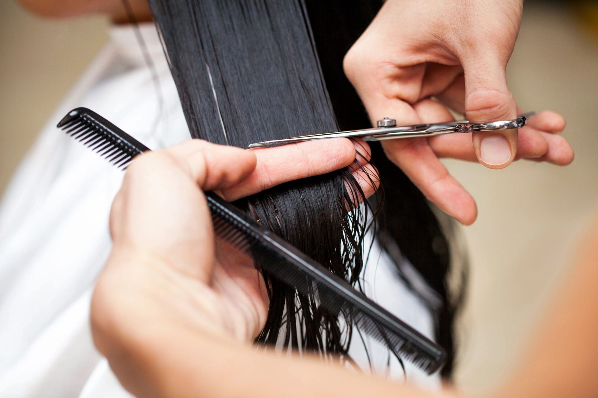 A woman with black hair having her tresses cut