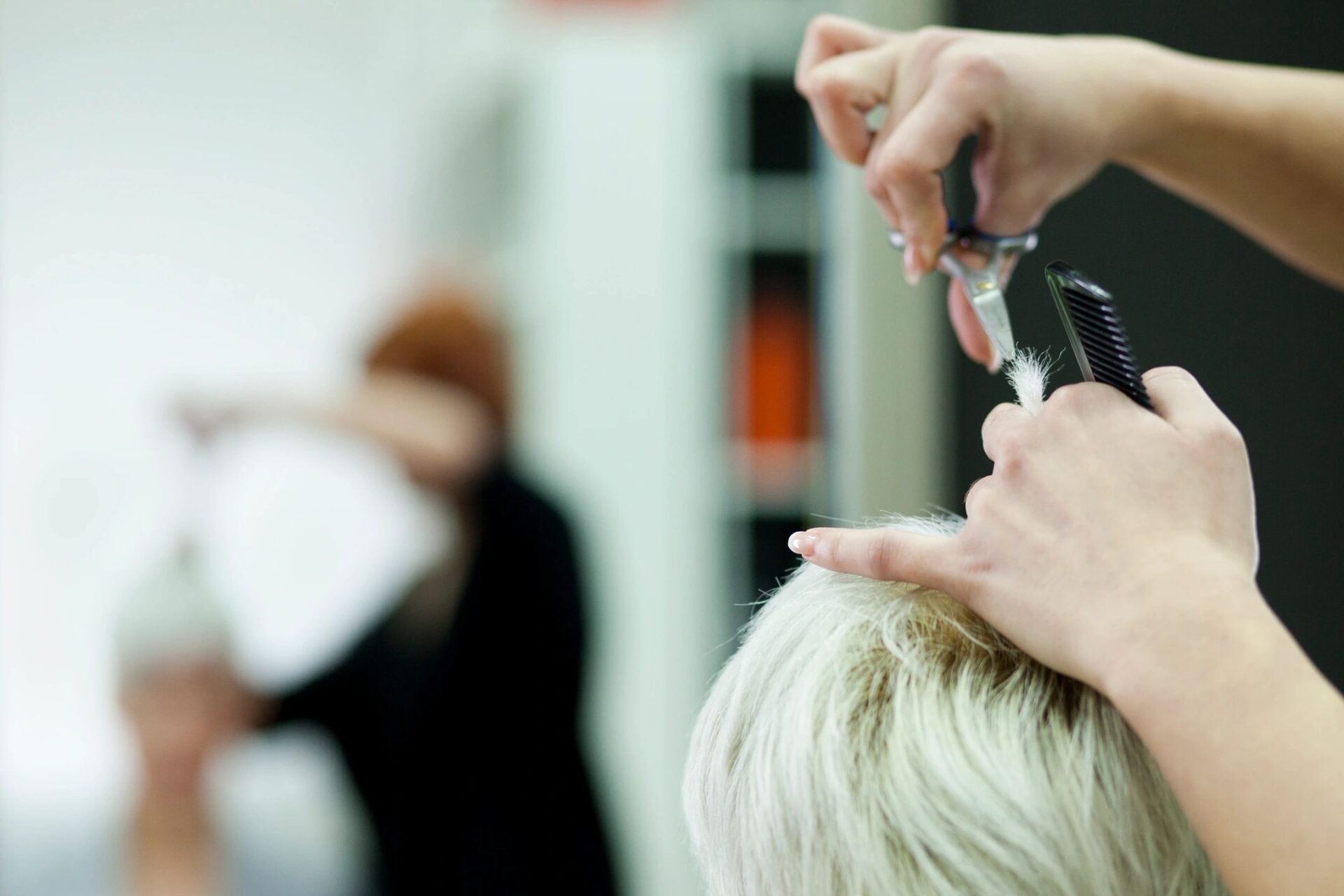 An individual with blonde hair having her tresses shortened