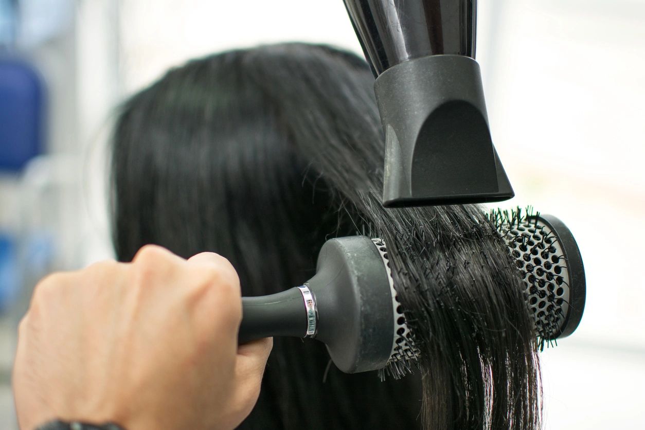 A woman with black hair having her tresses blow-dried